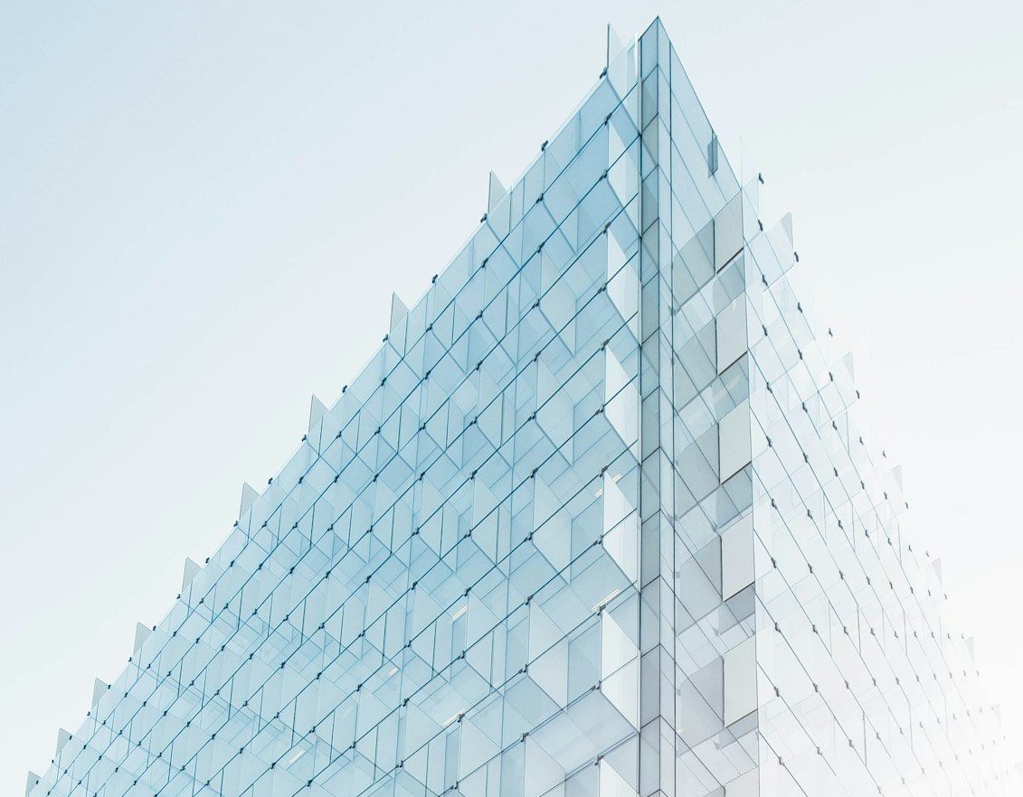 Façade moderne en verre, avec des lignes épurées et une lumière douce.