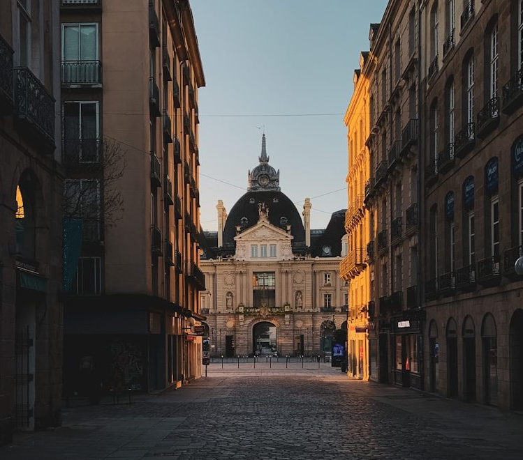 Rue pavée baignée de lumière dorée, bâtiment historique de Rennes à l'arrière-plan.